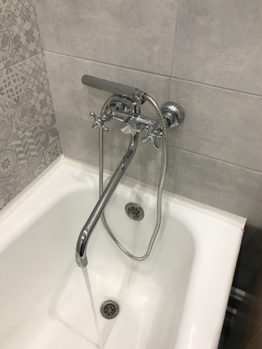 Изображение демонстрирует установленный смеситель с душем в ванной комнате. Проведены работы по монтажу оборудования, подключению к водопроводу, проверке герметичности соединений.