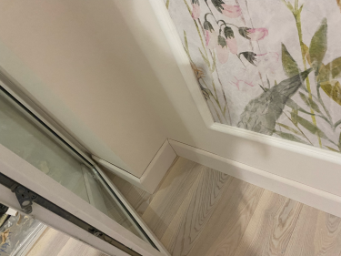 Установлен напольный плинтус, аккуратно закреплённый вдоль стены. Соединения ровные, без зазоров, обеспечивают плавный переход от пола к стене, создавая завершённый вид интерьера.