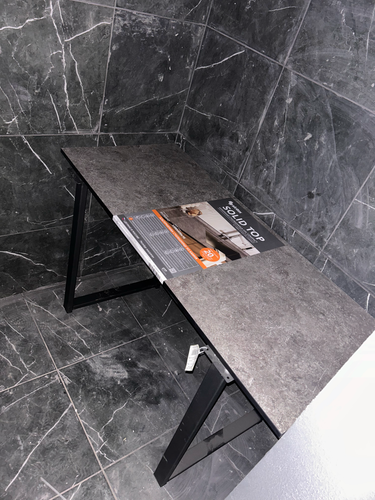 Установлена новая столешница из ДСП на кухне, закреплена на черных металлических опорах. Поверхность ровная, темного оттенка, гармонично сочетается с плиткой на стенах.