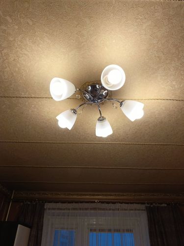 Люстра надежно закреплена на натяжном потолке, подключены все электрические элементы, обеспечено равномерное освещение, проверена безопасность конструкции, завершены финальные настройки.