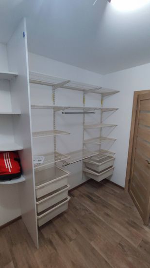 Установлены металлические полки в гардеробной. Конструкция закреплена на стене, обеспечивая надежность и устойчивость. Полки выровнены по уровню, что гарантирует их функциональность и долговечность.