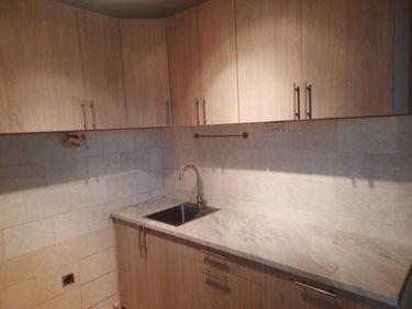 Смонтированы шкафы, установлена столешница из искусственного камня, врезана мойка, подключен смеситель, закреплены ручки. Завершена сборка кухонного гарнитура с отделкой.