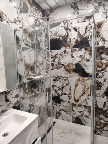 Установлены стеклянные перегородки, закреплены металлические профили, смонтирован душевой поддон, подключены водопроводные трубы, проверена герметичность соединений, выполнена отделка плиткой.