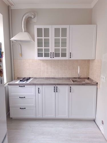 Установлены шкафы, закреплены фасады, смонтирована столешница, подключена мойка, вмонтирована варочная панель, установлена вытяжка, проведены коммуникации, завершена отделка стен.