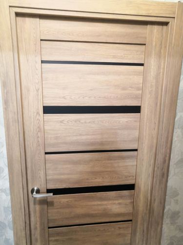 Установлена новая деревянная створка, закреплены петли, врезан замок, смонтирована ручка, отрегулированы зазоры, проверена плавность хода, выполнена отделка проема, завершены все монтажные работы.