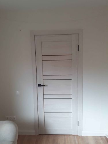 Изображена установленная складная дверь. Полотно закреплено в проеме, направляющие смонтированы. Ручка и замок установлены. Все элементы подогнаны, обеспечивая плавное функционирование.