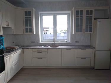 Собрана кухня: установлены шкафы, смонтирована столешница, врезана мойка, подключена техника, закреплены ручки, отрегулированы дверцы. Завершена отделка, все элементы на месте.