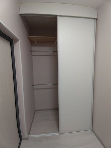 Встроена деревянная полка в нишу, закреплена на металлических кронштейнах. Установлены две штанги для одежды, обеспечивая дополнительное место для хранения в гардеробной.