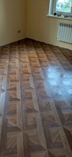 Завершена укладка ламината на подготовленное основание. Пол ровный, без зазоров, с четким рисунком. Углы и стыки обработаны, поверхность гладкая, без дефектов.