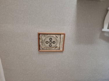 На стене закреплено декоративное панно в деревянной раме, выполнено аккуратно и надежно, обеспечивая эстетичный вид и гармоничное дополнение интерьера.