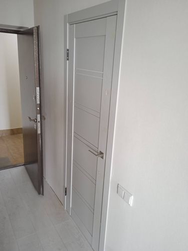 Изображена установленная складная дверь, закрепленная в проеме. Завершены монтажные работы, включая фиксацию направляющих, крепежа и ручек. Конструкция гармонично вписывается в интерьер.