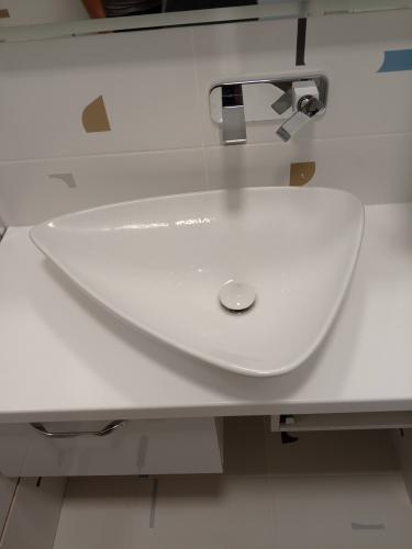 Изображена раковина, установленная на белой столешнице с современным смесителем. Работа завершена: сантехника полностью демонтирована, поверхность очищена, коммуникации отсоединены.