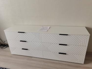 Собран белый комод с тремя ящиками, установлены ручки, выровнены фасады, прикреплены направляющие, проверена устойчивость, закреплены детали, проверена функциональность.