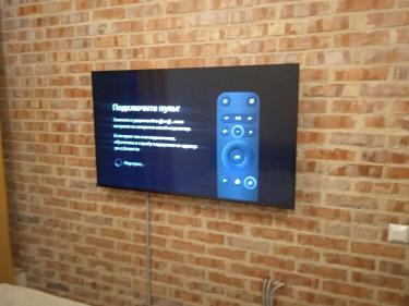 Закреплен кронштейн на кирпичной стене, установлен телевизор, подключены кабели, обеспечена надежная фиксация и аккуратный внешний вид.