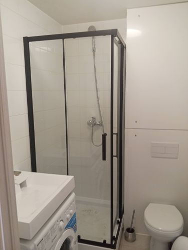 Выполнен монтаж стеклянных панелей, установлены дверцы, закреплены профили, подключен душевой шланг, проверена герметичность соединений, обеспечена устойчивость конструкции в ванной комнате.