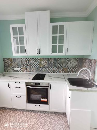 Гармонично установлены белоснежные дверцы с аккуратными ручками. Эстетично оформлены стеклянные вставки. Завершён монтаж фасадов, подчёркивающих стиль кухни.