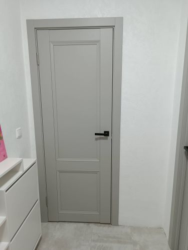 Установлена светлая одностворчатая дверь с аккуратной фурнитурой, ровно закреплена в проеме, выполнены отделочные работы, обеспечена плавная работа механизма, завершена установка наличников.