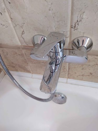 Изображен завершенный процесс снятия смесителя с раковины. Удалены крепления, отключены водопроводные шланги, устранены остатки герметика. Место подготовлено для установки нового оборудования.