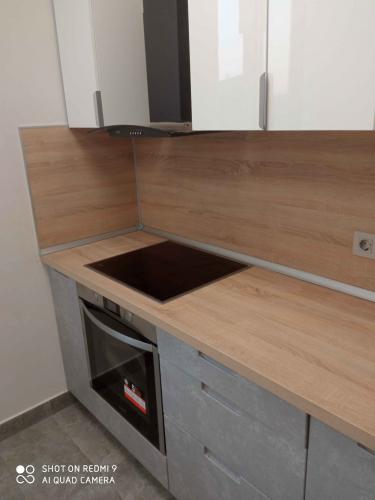 Изображена современная кухня с новой варочной панелью и вытяжкой. Белые шкафы и деревянная столешница создают стильный интерьер.