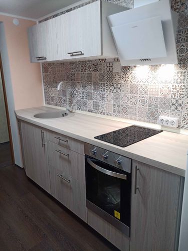 Установлены кухонные шкафы, смонтирована столешница, врезана варочная панель, подключена мойка, закреплена вытяжка, оформлен фартук плиткой, установлены ручки и розетки.