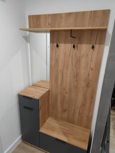 Собран шкаф с полкой, крючками и зеркалом. Установлены дверцы, закреплены элементы. Компактная конструкция из дерева и металла завершена, готова к использованию.