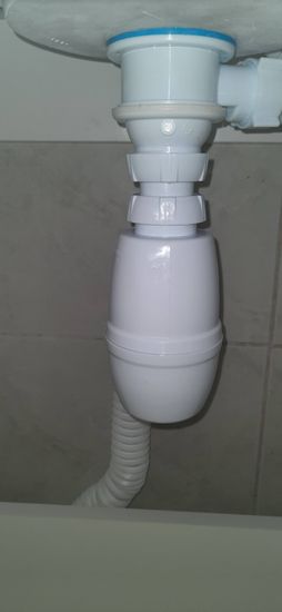 Установлен сливной сифон под раковину, подключены трубы, герметично закреплены соединения, проверена работа системы, обеспечена надежная фиксация всех элементов.