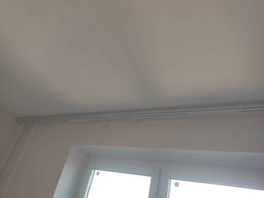 На стене закреплён карниз над окном. Установлены крепления, обеспечивающие надёжность конструкции. Работа выполнена аккуратно и ровно, без видимых дефектов.