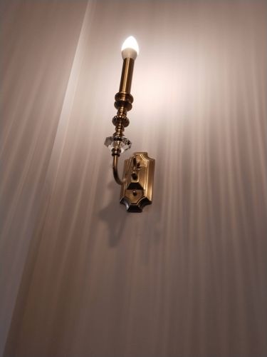 Изображена завершенная установка светильника на натяжной поверхности. Проведены работы по креплению, подключению к электросети и проверке функционирования осветительного прибора.