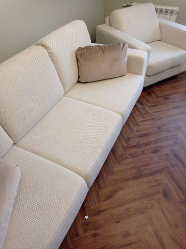 Собран диван: установлены каркас, подлокотники, спинки, подушки. Все элементы надежно закреплены, обеспечена устойчивость и комфорт. Завершено размещение на полу.