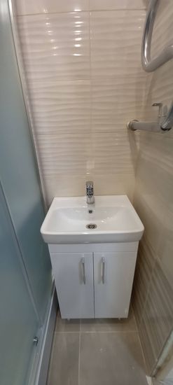 Установлена душевая конструкция, закреплены стенки, герметично обработаны швы, подключены коммуникации, проверена работа смесителя, установлена раковина с тумбой, завершены отделочные работы.