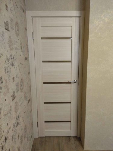 Установлена новая дверь, уменьшен проем, выровнены стены, добавлены наличники, обновлено покрытие пола, поклеены обои. Завершено оформление, обеспечена функциональность и эстетика.