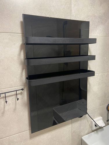 Установлен современный черный прибор на стену в ванной комнате, подключен к электросети, проверена работоспособность, обеспечена надежная фиксация и безопасное использование.