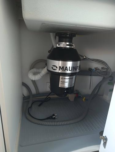 Установлен и подключен измельчитель под раковиной, подключены трубы и электропитание, проверена герметичность соединений, устройство готово к использованию.