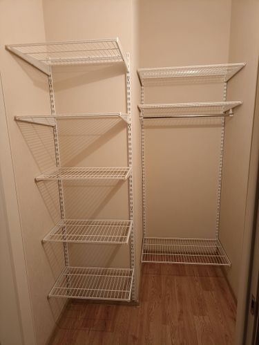 Установлены металлические стеллажи на стену, обеспечивающие прочное крепление и устойчивость. Полки ровно выровнены, создавая функциональное пространство для хранения.