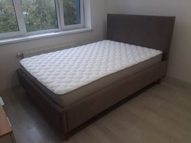 Собрана мебель: установлены боковины, закреплено изголовье, прикреплены ножки, уложен матрас. Все элементы надежно соединены, конструкция устойчива, готова к использованию.