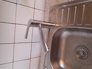 Изображение демонстрирует завершенный демонтаж кухонного гарнитура: удалены шкафы, снята столешница, отсоединены коммуникации, оставлен смеситель и мойка. Стены очищены от крепежей.