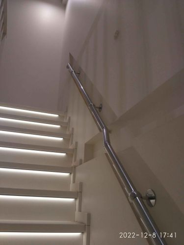 Установлены металлические перила вдоль лестницы с подсветкой. Стены окрашены в светлый тон, создавая современный стиль. Завершена работа по монтажу и декорированию пространства.