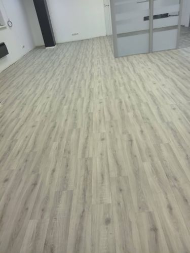 На ровное основание настелен линолеум с имитацией древесины, без зазоров и складок, обеспечивая гладкую и эстетичную поверхность.