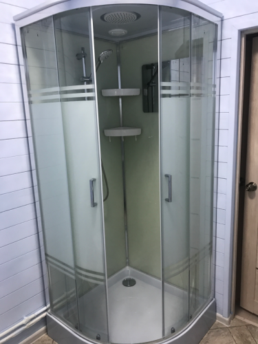 Установлена современная кабина: закреплены стеклянные панели, подключены смеситель и лейка, герметизированы швы, смонтирован поддон, проверена герметичность, установлены полки.