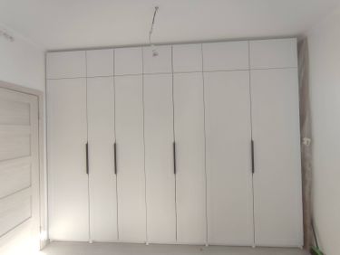 Установлен встроенный шкаф с белыми дверцами и черными ручками, выровнены стены, покрашены в светлый тон, проведена электропроводка для освещения, закреплены плинтусы.