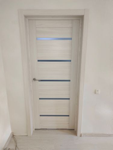 Установлена новая дверь с петлями, врезан замок, закреплена ручка. Коробка выровнена, наличники зафиксированы. Полотно аккуратно подогнано, обеспечена плавная работа.