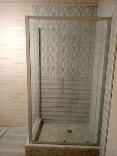 Установлена стеклянная перегородка с дверцей, закреплены профили, герметично обработаны швы, проверена устойчивость конструкции, обеспечен доступ к сливу, завершена отделка плиткой.