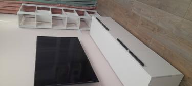 Установлена белая полка с несколькими уровнями рядом с телевизором. Все элементы надежно закреплены, обеспечивая устойчивость и функциональность конструкции в интерьере.