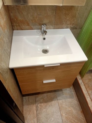 Установлена новая раковина с тумбой, подключены водопроводные трубы и слив, закреплен смеситель, проверена герметичность соединений, выполнена отделка стен плиткой.