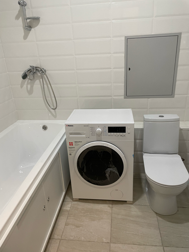 Изображена завершенная установка бытового прибора: подключены водопровод и слив, проверена герметичность соединений, устройство размещено на выбранном месте, выполнено тестирование работы.