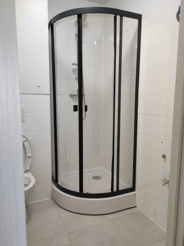 Установлена душевая кабина с полукруглым поддоном, закреплены стеклянные двери, подведены коммуникации, проверена герметичность соединений, завершена отделка стен и пола.