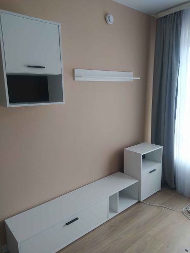 Установлены и закреплены полки, шкафы и тумбы. Все элементы мебели собраны и размещены вдоль стены, обеспечивая устойчивость и функциональность. Завершено оформление интерьера.