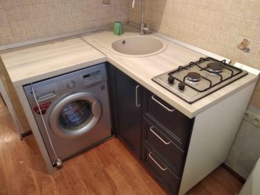 Установлены шкафы, закреплена столешница, вмонтированы раковина и варочная панель, подключена стиральная машина. Все элементы аккуратно подогнаны, обеспечена функциональность.