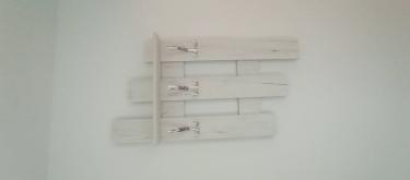 На стене закреплена деревянная конструкция с тремя металлическими крючками. Элементы прочно зафиксированы, обеспечивая надежное использование для подвешивания одежды.