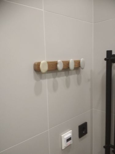 На стене установлена деревянная вешалка с четырьмя овальными крючками. Крепление выполнено аккуратно, конструкция надежно закреплена на плитке.